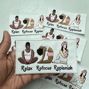 May include: Embroidered patches with yoga poses and the words "Relax, Refocus, Replenish." Each patch features a different pose, with figures in white, pink, and brown. The patches are rectangular with white borders.