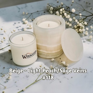 May include: A white ceramic mug with a black handle and the text "But First, Coffee" in a bold, black font. The mug is set against a blurred background, suggesting a cozy setting.