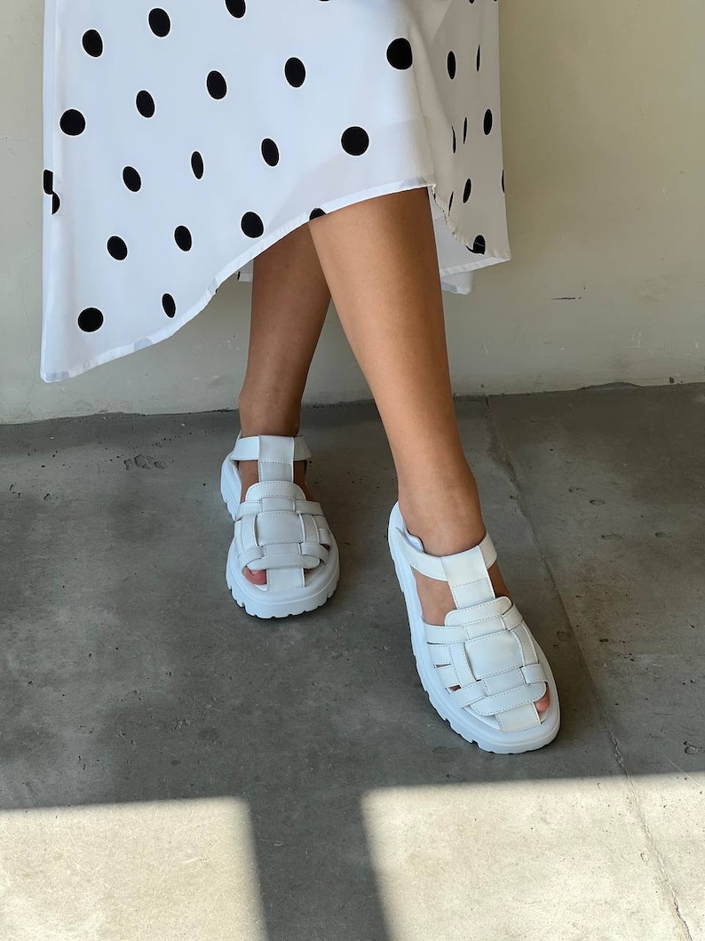 May include: White leather sandals with a chunky platform sole and a woven strap design.