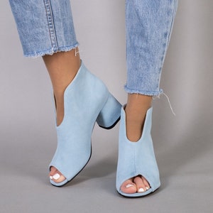 Könnte beinhalten: Ein Paar hellblaue Wildlederstiefeletten mit Peeptoe und Blockabsatz.