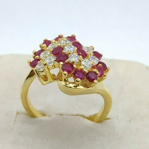 May include: A gold ring featuring a large cluster of red and white stones. The stones are set in a swirling design.