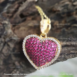 Può includere: Una collana con un ciondolo a forma di cuore in oro, incrostato di rubini rossi e diamanti bianchi.