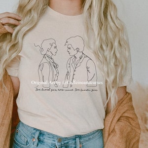 Puede incluir: Una camiseta beige con un dibujo en línea negra de dos personas que se miran. El texto "Original Art by @Caffeineandcurses" y "I've loved you ever since I knew you" está impreso debajo del dibujo.