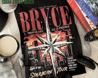 May include: A black t-shirt featuring a graphic print with the text JELLY JUBILEE PRESENTS BRYCE, THROUGH LOVE ALL IS POSSIBLE, LIGHT IT UP, and STARBORN TOUR. The design includes a large central star, a city skyline, and sunset colours.
