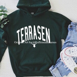 Puede incluir: Una sudadera con capucha verde oscuro con la palabra "TERRASEN" en texto blanco en la parte delantera. El texto est&aacute; en una fuente arqueada. Debajo del texto est&aacute; la frase "Original Art by @caffeinandcurses" en texto blanco. Un gr&aacute;fico de cabeza de ciervo blanco est&aacute; debajo de la frase.