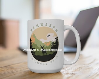 May include: White ceramic mug featuring a graphic of a deer silhouette in a woodland scene. The text "TERRASEN NATIONAL PARK" is printed in a circle around the image. The text "Original Art by @Caffeineandcurses" is printed below the image.