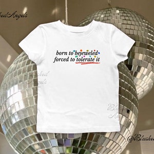 Camiseta infantil Born to Bejeweled Forced to Tolerate It da Taylor | Camiseta Coquette, camiseta infantil dos anos 90, camiseta Evermore, produtos da Taylor, camiseta Midnights, turnê Eras