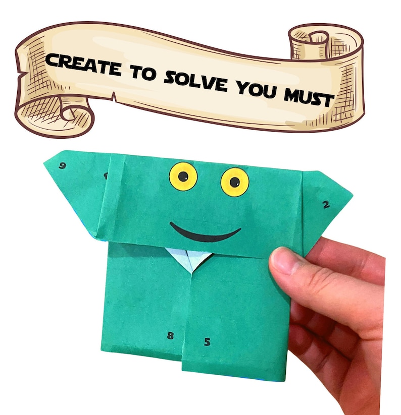 Może przedstawiać: Zielona żaba origami z uśmiechającą się twarzą i ż&oacute;łtymi oczami. Żaba jest ponumerowana 2, 5, 8 i 9 na swoim ciele. Tekst "CREATE TO SOLVE YOU MUST" jest napisany na zwoju nad żabą.