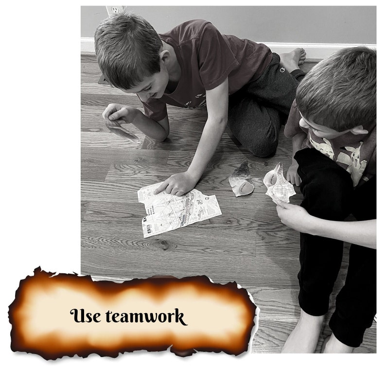 May include: Two children are working together on a jigsaw puzzle on a wooden floor. The puzzle pieces are scattered on the floor. The text "Use teamwork" is written on a burnt piece of parchment paper.
