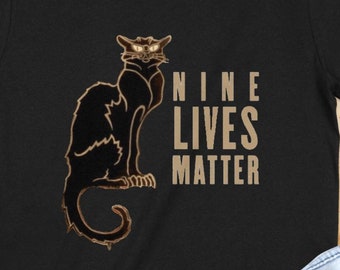 May include: Black t-shirt with a black cat illustration and the text "NINE LIVES MATTER" in gold lettering.