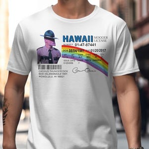 May include: White t-shirt featuring a graphic of a Hawaii Mogger License. The design includes a photo of a person in a police uniform, a rainbow, and text with details like a date of birth and address.