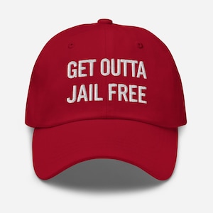 Pode incluir: Boné de beisebol vermelho com texto bordado em branco que diz "GET OUTTA JAIL FREE".