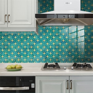 Puede incluir: Un salpicadero de cocina con un patrón geométrico de color verde azulado y dorado. El salpicadero está hecho de azulejos con un acabado brillante. Los azulejos están dispuestos en un patrón repetitivo de círculos superpuestos.