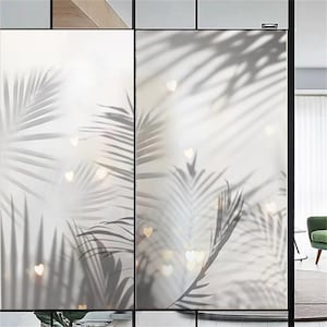 May include: A frosted glass window film featuring a palm leaf shadow pattern and small heart-shaped cut-outs. The film is designed to offer privacy and a decorative touch to windows.