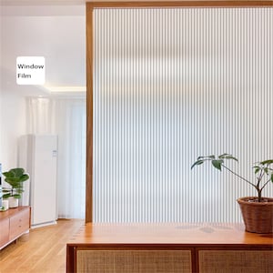 Könnte beinhalten: Eine weiße Fensterfolie mit vertikalen Linien, die auf eine Glastür in einem modernen Haus angebracht ist. Die Folie bietet Privatsphäre und lässt gleichzeitig natürliches Licht durch. Die Folie ist auf einer Glastür mit einem Holzrahmen angebracht.