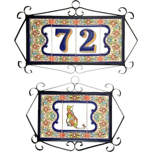Puede incluir: Dos placas rectangulares de pared enmarcadas en hierro forjado negro con volutas. La placa superior muestra el número 72 en azul con sombreado naranja. La placa inferior presenta una ilustración de un gato multicolor. Bordes florales.
