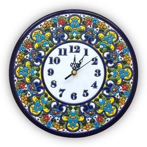 Könnte beinhalten: Runde Wanduhr aus Keramik mit weißem Zifferblatt und schwarzen Ziffern. Die Uhr hat einen dekorativen Rand mit einem blauen, gelben, grünen und roten Blumenmuster. Die Zeiger der Uhr sind schwarz und goldfarben.