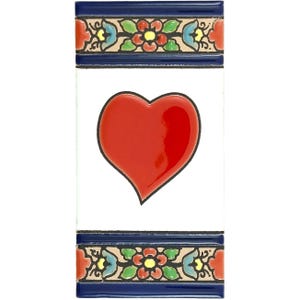 May include: A rectangular ceramic tile featuring a glossy red heart. The white tile is framed by a dark blue border with floral patterns in red, yellow, green, and beige. The design is reminiscent of traditional tilework.