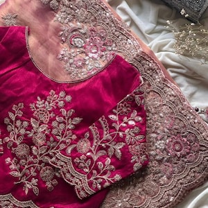 May include: A magenta-colored, long-sleeved blouse with intricate floral embroidery and a matching sheer, embroidered shawl. The shawl and blouse are embellished with silver sequins. The ensemble is displayed on a white surface.