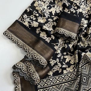 Puede incluir: Sari de estampado floral blanco y negro con borde dorado y ribete de encaje festoneado. El sari tiene un patrón geométrico en la parte inferior.