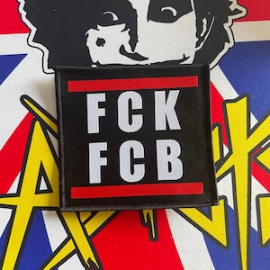 Peut inclure: Patch carré noir et rouge avec du texte blanc qui dit "FCK FCB".