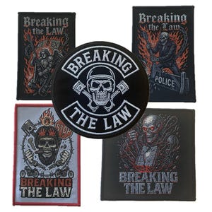 以下が含まれることがあります： 「Breaking the Law」の刺繍パッチのコレクション。パッチには、スカルグラフィック、炎、バイクをテーマにした画像が描かれています。中央のパッチは丸く、ヘルメットをかぶったスカルと交差したピストンが描かれています。