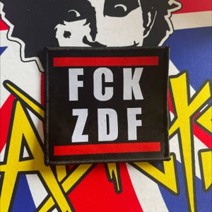 May include: Black patch with red trim and white text that reads "FCK ZDF".