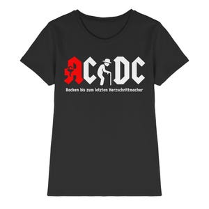 Könnte beinhalten: Schwarzes T-Shirt mit weißem und rotem Aufdruck. Der Aufdruck zeigt die Buchstaben "AC/DC" mit einem stilisierten Bild einer Person mit Gehstock und dem Text "Rocken bis zum letzten Herzschrittmacher" darunter.