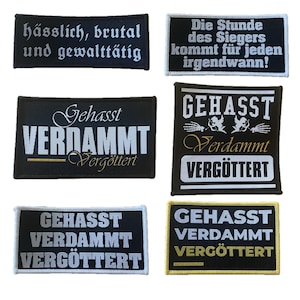 Può includere: Una collezione di toppe rettangolari nere con testo bianco e oro. Le toppe presentano frasi in tedesco, tra cui "hässlich, brutal und gewalttätig" e "Gehasst, Verdammt, Vergöttert." Alcune toppe hanno elementi decorativi.