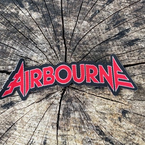 May include: A black and red embroidered patch with the word "AIRBOURNE" in red lettering.