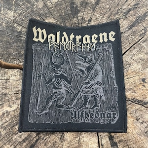 May include: Black embroidered patch with the text "Waldtraene" and "PNNWRFMMH" in gold lettering. The patch features a black and white image of two figures with swords, and the text "Ulfhednar" at the bottom.
