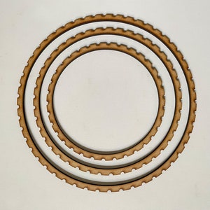May include: Three concentric wooden rings with scalloped edges. The rings are unfinished and have a natural wood color.