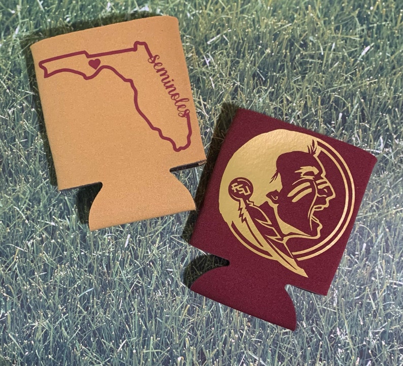 Op de afbeelding: Twee schuimrubberen blikjeskoelers, een is beige met een rode omtrek van de staat Florida en het woord "Seminoles" erop gedrukt, de andere is bordeauxrood met een gouden omtrek van een Indiaans hoofd met een veer en de letters "FSU" erop gedrukt.
