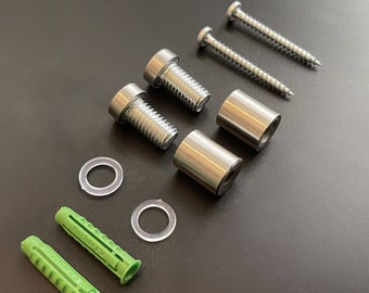 May include: An assortment of hardware components, including silver screws, bolts, cylindrical spacers, clear washers, and green wall anchors. The items are arranged on a dark surface, suggesting a set for installation or assembly.