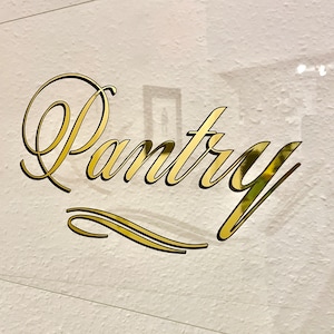 May include: A white ceramic mug with a black handle and the text "But First, Coffee" in a handwritten style. The mug is on a white surface. The mug is 4 inches tall.
