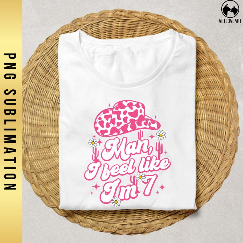 May include: White t-shirt with a pink cow print hat, cactus, and the text "Man, I feel like I'm 7".