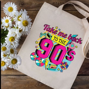 May include: A white tote bag with a colorful graphic design featuring the text "Take me back to the 90's". The design includes retro icons like a cassette tape, a game controller, a Tamagotchi, and a Rubik's Cube.