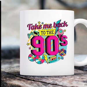 May include: White ceramic mug with a colorful graphic design featuring the text "Take me back to the 90's" and retro icons like a cassette tape, a game controller, and a Tamagotchi.
