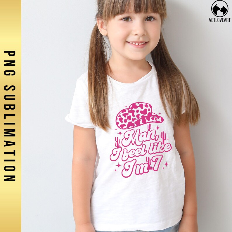 May include: A white t-shirt with a pink graphic design of a cowboy hat, cacti, and the text "Man, I feel like I'm 7".
