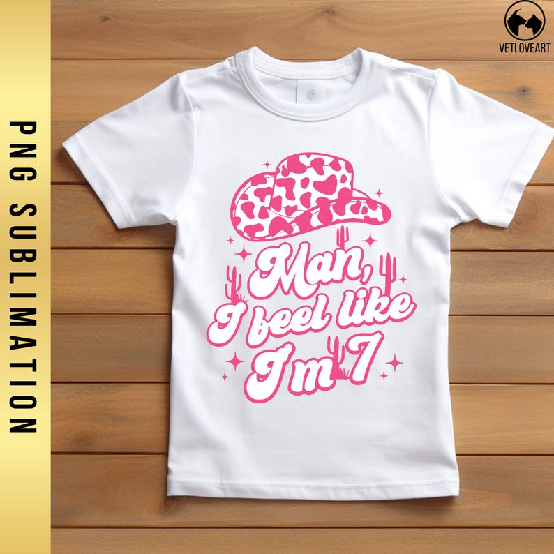 May include: White t-shirt with a pink cow print cowboy hat, cacti, and the text "Man, I feel like I'm 7".
