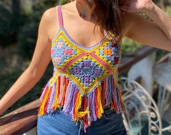 May include: A colorful crochet top with a geometric pattern and fringe trim. The top is made in shades of pink, yellow, blue, and purple.
