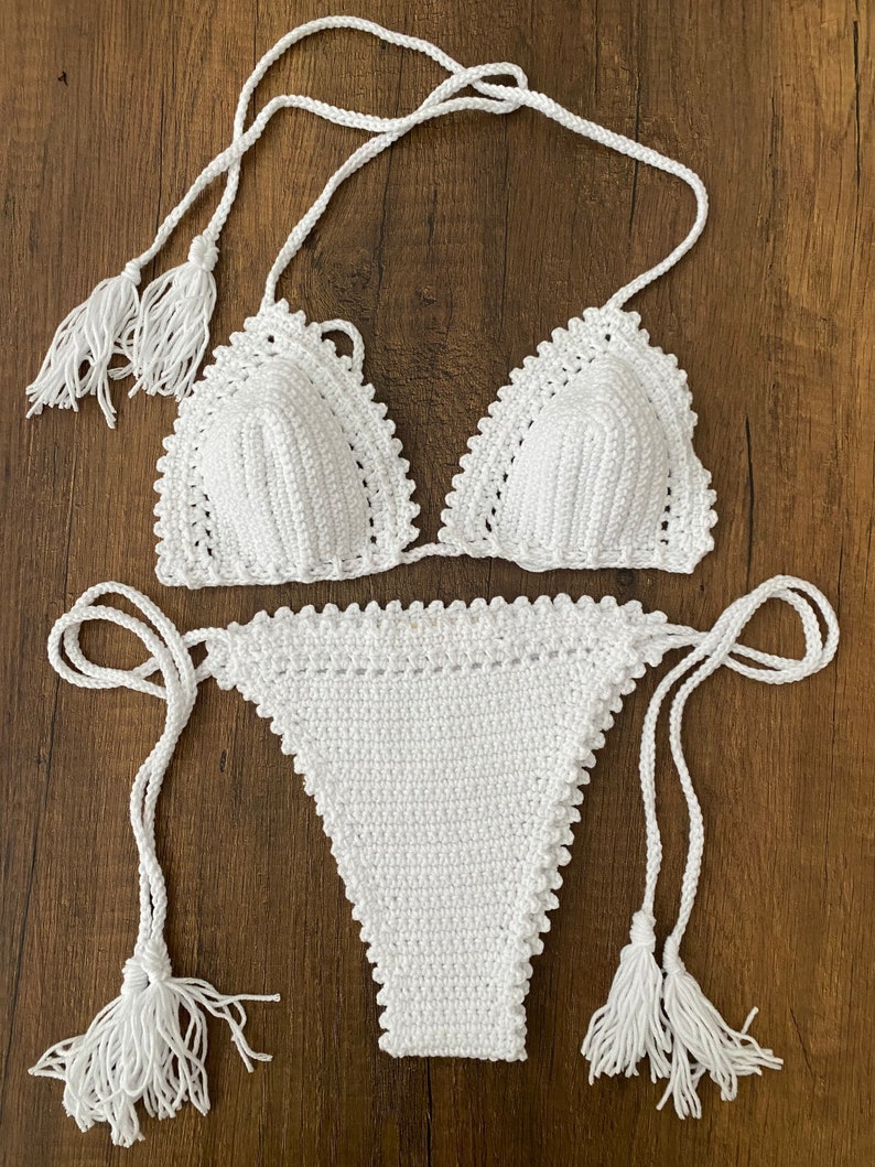 May include: White crochet bikini top and bottom with tassel ties.