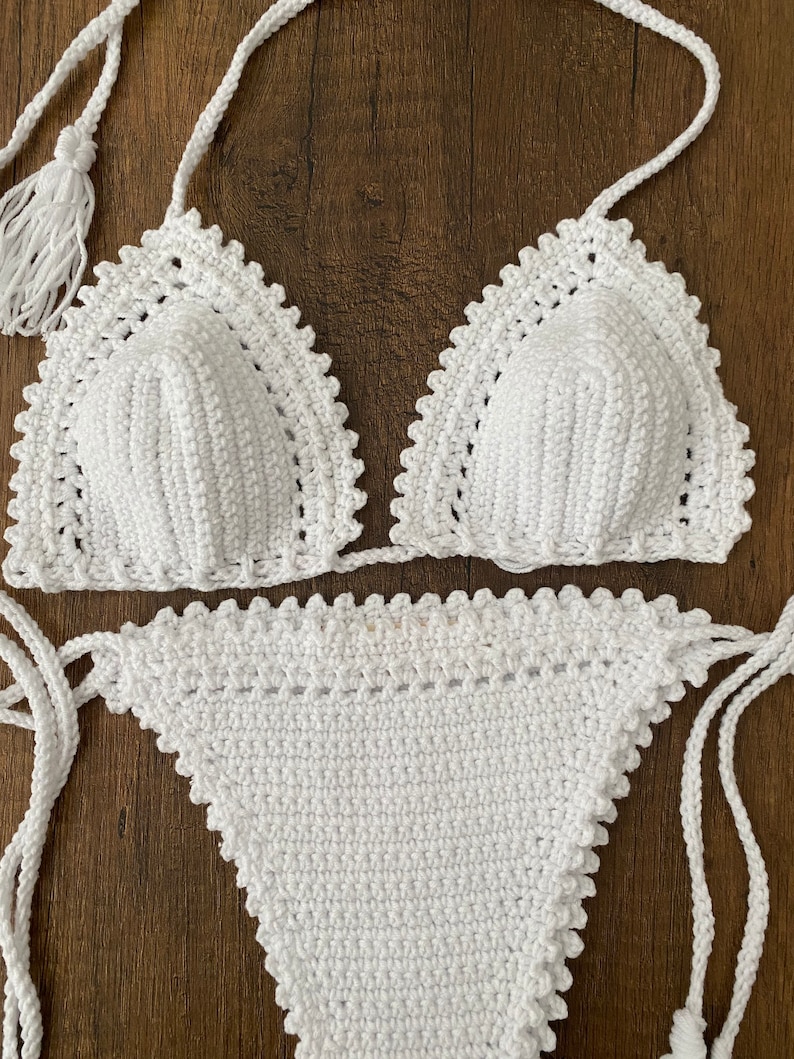 May include: White crochet bikini top and bottom with a scalloped edge. The top has a triangle shape and the bottom is a high-waisted style.