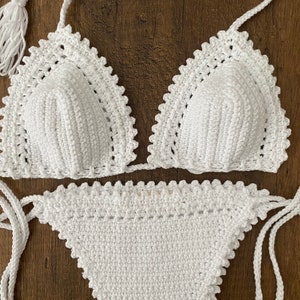 May include: White crochet bikini top and bottom with a scalloped edge. The top has a tie closure at the neck and back. The bottom has a tie closure on the sides.
