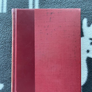 May include: A red hardcover book with a spine that is a darker shade of red.