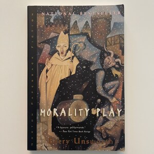 May include: A book cover with a snowy scene featuring a man in a white robe and a horned figure. The title of the book is "Morality Play" by Barry Unsworth. The book is a National Bestseller.
