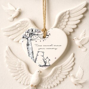 May include: A heart-shaped memorial ornament with the text "Time cannot erase your memory." The ornament features a tree and two animal figures. White doves and angel wings surround the ornament, creating a serene and comforting scene.