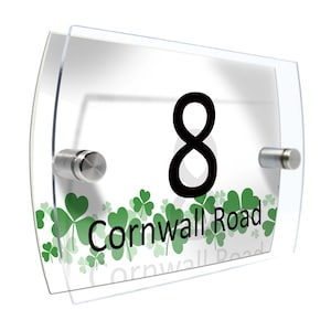 Puede incluir: Letrero de número de casa de acrílico transparente con el número 8 en negro. El letrero presenta el texto "Cornwall Road" en verde, junto con diseños de tréboles verdes. Montado con separadores plateados.