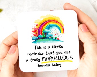Può includere: Un sottobicchiere bianco con un arcobaleno, alberi e il testo "This is a little reminder that you are a truly MARVELLOUS human being".