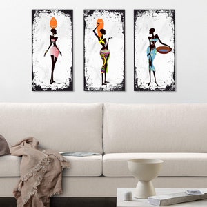 May include: Three framed art prints featuring stylized black figures of women in colorful clothing. The prints are hung on a white wall above a white couch.